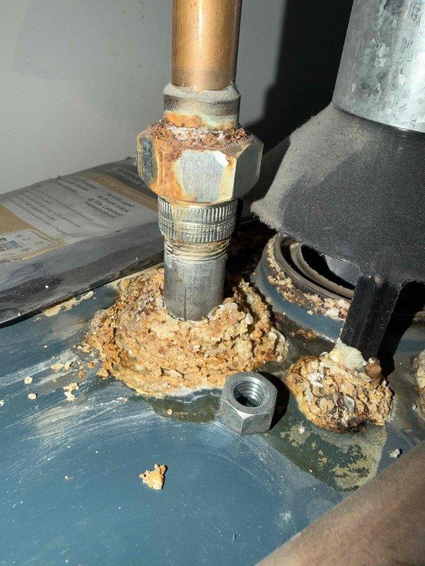 Performed comprehensive maintenance on non-condensing gas furnace and completed BWC service. Documented significant corrosion at plumbing connection point with extensive rust and mineral buildup on copper pipe fitting. Observed Carrier unit with proper PVC ventilation pipes and inspected surrounding HVAC components including ductwork and connections.
