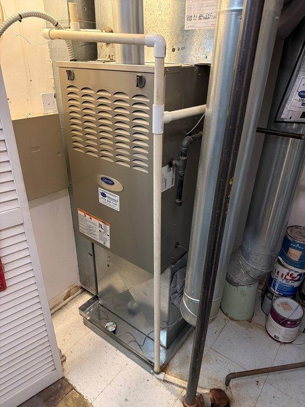 Performed comprehensive maintenance on non-condensing gas furnace and completed BWC service. Documented significant corrosion at plumbing connection point with extensive rust and mineral buildup on copper pipe fitting. Observed Carrier unit with proper PVC ventilation pipes and inspected surrounding HVAC components including ductwork and connections.