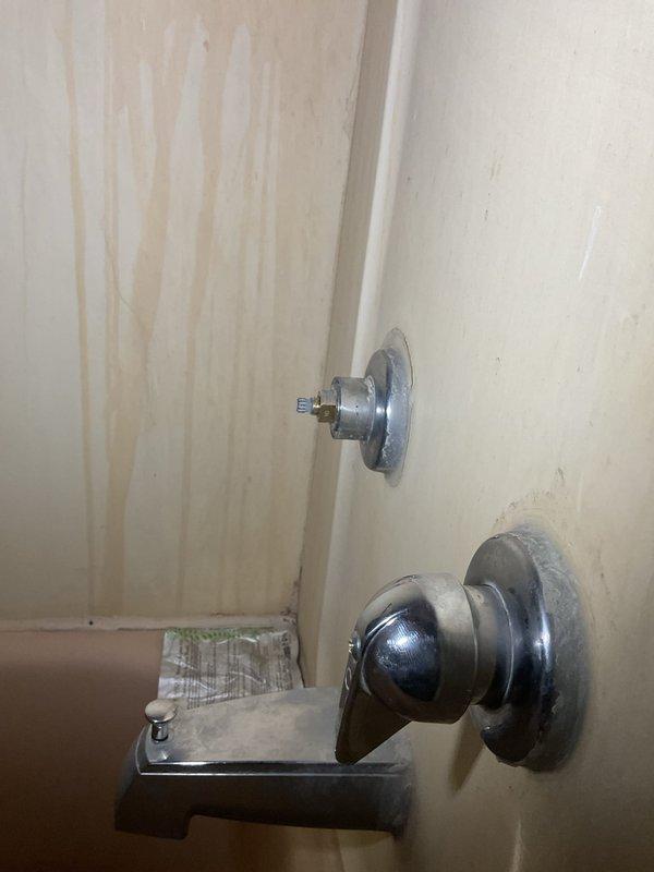 Conducted plumbing estimate for bathroom fixtures showing significant wear. Assessed wall-mounted hot and cold faucet handles in both bathtub/shower and sink areas that were loose and require replacement. Documented water staining on surrounding surfaces and mineral deposits around drain areas, indicating ongoing issues with the current fixtures.