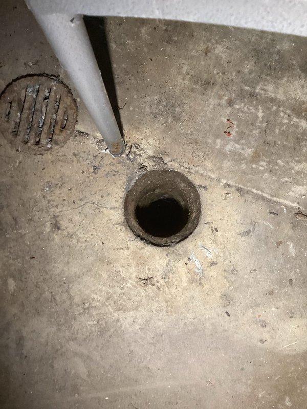 Performed main drain cleanout with camera inspection in basement utility area. Accessed floor drain opening, cleared blockage, and conducted video camera inspection to verify proper flow and assess drain line condition throughout system. Documented drain condition and work completed with photographic evidence showing cleanout access point and surrounding plumbing infrastructure.