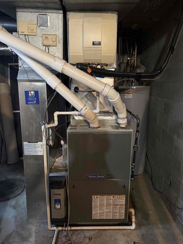 Provided comprehensive replacement estimate for 15-year-old American Standard furnace system located in basement mechanical room. Unit diagnosed with cracked heat exchanger and multiple major component failures requiring full system replacement. Documented existing equipment configuration including PVC venting system, electrical connections, and clearance measurements to ensure proper specifications for new installation.