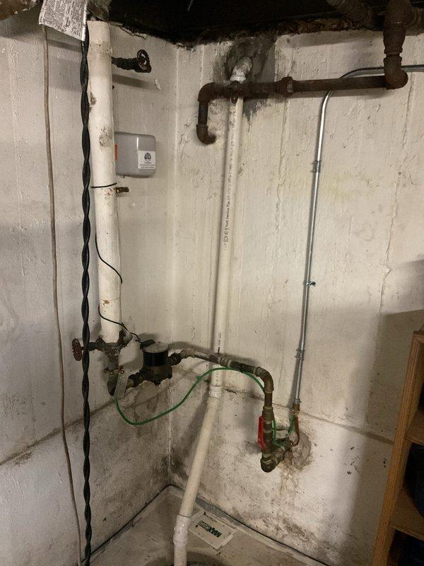 Responded to service call for clogged bathroom sink in residence with century-old plumbing infrastructure. Upon arrival, conducted comprehensive inspection of plumbing system including basement mechanical area and bathroom fixtures. Documented existing conditions of aged piping system, noting combination of original dark metal pipes and newer PVC installations with multiple connection points and shutoff valves. 

In bathroom area, observed significant mineral deposit accumulation on tub spout and fixtures, indicating hard water conditions throughout the property. Assessed condition of bathroom plumbing connections and drainage system. Photographed plumbing infrastructure and fixture conditions for service records. Recommended addressing mineral buildup on fixtures and potential preventative maintenance given age of plumbing system to prevent future drainage issues.
