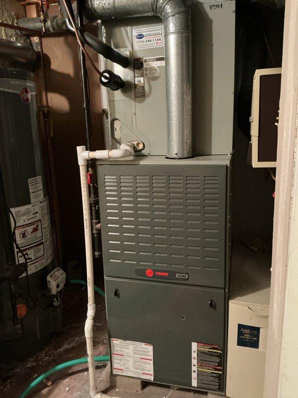 Completed comprehensive air conditioning maintenance service per agreement terms. Performed system inspection of Trane HVAC unit, including visual assessment of furnace, ductwork connections, and associated mechanical components. Documented equipment condition with photos showing proper installation of furnace unit, metallic ductwork routing, PVC drainage system, and wall-mounted thermostat controls.

Conducted temperature differential measurements using calibrated digital thermometer, recording evaporator coil performance data. Observed significant condensation accumulation on interior metal surfaces and air handler panels, indicating proper cooling operation and adequate refrigerant charge. Verified flexible ductwork connections and inspected overall system functionality in basement mechanical room environment.