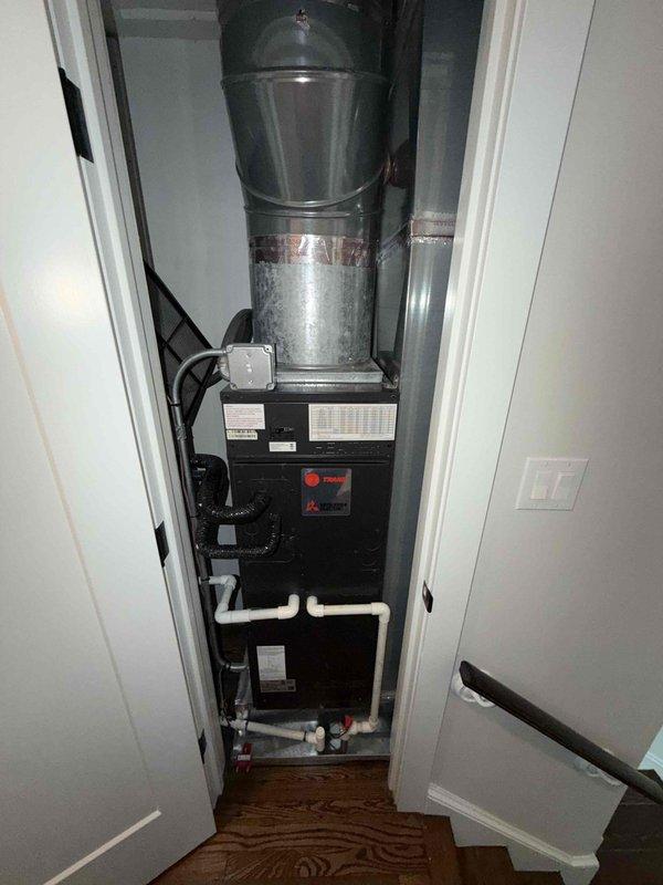 Completed comprehensive maintenance inspection on two furnace systems, humidifier, and water heater per agreement terms. Documented system conditions with photos showing Trane furnace installation in utility closet and HVAC components in attic space, noting significant condensation buildup on ductwork indicating high humidity levels or temperature differential. All equipment operational at time of inspection with proper drainage configuration and electrical connections verified.