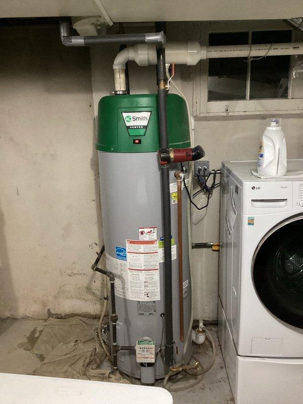 Responded to emergency service call for leaking 20-year-old A.O. Smith tanked water heater located in basement utility area. Upon arrival, conducted visual inspection of unit and surrounding plumbing connections, documenting existing conditions with photographs. Assessed water heater showing signs of age-related deterioration, multiple pipe connections including copper supply lines, PVC venting, pressure relief valve with discharge piping, and various shut-off valves. Unit displayed manufacturer specifications and energy compliance labels on exterior tank body with characteristic green crown assembly.