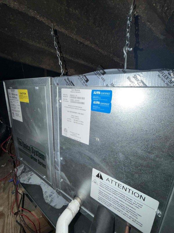 Completed comprehensive cooling check on air conditioning system and air handler general service in attic installation. Performed thorough inspection of suspended air handler unit, verified proper chain mounting and structural support from ceiling joists, and documented all manufacturer labels and AHRI certification stickers. Inspected electrical components including relay switch with red wiring, confirmed proper connections and functionality. Verified PVC condensate drain line installation and routing. System found operating within normal parameters with all safety devices and controls functioning properly.