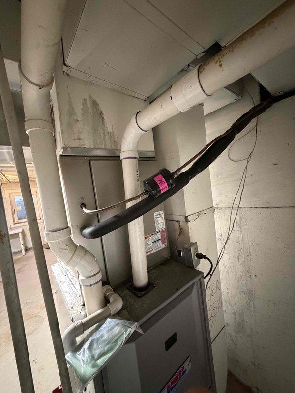Completed comprehensive furnace replacement estimate for a 20-year-old HVAC system located in basement utility area with easy access. Evaluated existing gray metal furnace unit and assessed current installation including associated ductwork, PVC venting system, and electrical connections to determine feasibility of replacement versus continued repairs given the age and condition of the equipment.