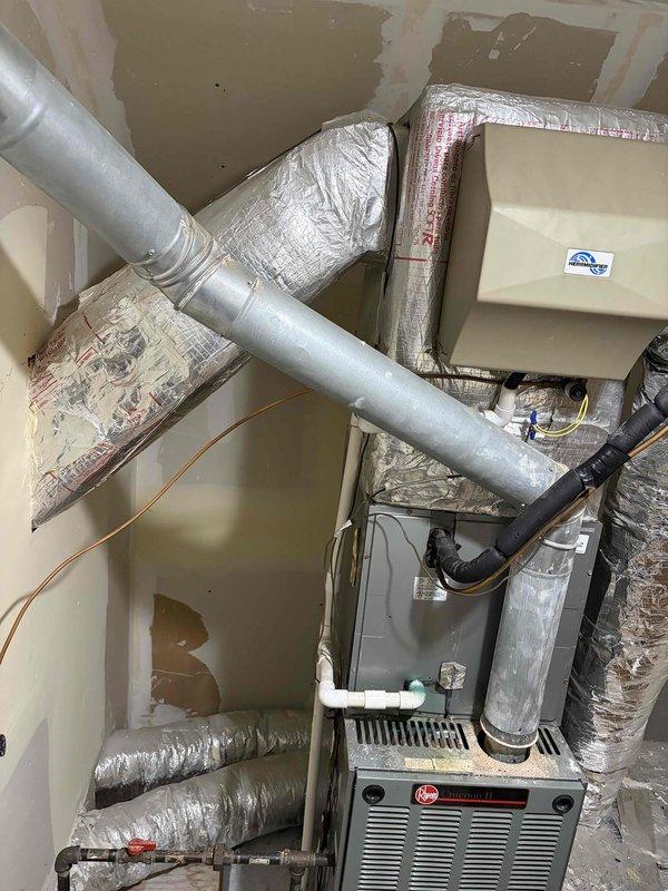 Conducted comprehensive HVAC system evaluation for 22-year-old residential heating and cooling equipment located in basement utility area. Assessed existing Rheem furnace, air handler unit, ductwork configuration, refrigerant lines, and associated mechanical components to provide complete system replacement recommendations. Documented current installation conditions including flexible ductwork connections, PVC condensate drainage, copper refrigerant piping, and overall system layout to determine optimal replacement specifications and equipment requirements.
