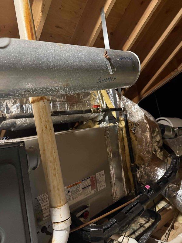 Completed HVAC estimate for replacement of 10-year-old attic furnace unit experiencing multiple critical failures including defective ECM motor, oil leak, and improperly installed flue pipe. Documented existing system configuration with air handler and ductwork in attic space, photographed current thermostat displaying 69°F setting, and assessed customer's request for equipment relocation to washing machine room for improved accessibility and serviceability.