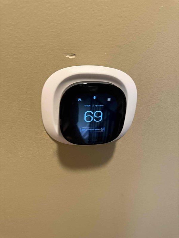 Completed HVAC estimate for replacement of 10-year-old attic furnace unit experiencing multiple critical failures including defective ECM motor, oil leak, and improperly installed flue pipe. Documented existing system configuration with air handler and ductwork in attic space, photographed current thermostat displaying 69°F setting, and assessed customer's request for equipment relocation to washing machine room for improved accessibility and serviceability.