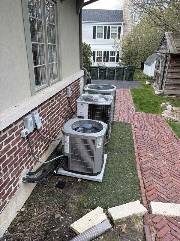 Conducted comprehensive HVAC system assessment for complete replacement of two air conditioning units and one furnace. Performed detailed measurements of existing ductwork to verify compatibility with proposed equipment specifications. Documented current system configuration including three outdoor condenser units positioned along building exterior on concrete pads with electrical connections and conduit routing. Evaluated duct insulation condition and clearances in mechanical space. Assessed installation site accessibility, including brick foundation mounting requirements and existing concrete pad placements. Photographed existing equipment layout and ductwork dimensions to support equipment sizing recommendations and replacement planning. Provided technical specifications and replacement options for complete system upgrade.