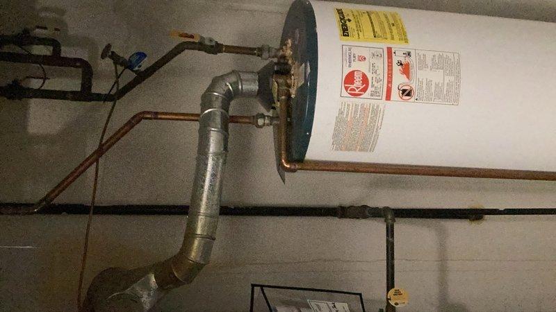 Completed installation of a 50-gallon Bradford White residential water heater in basement utility area. Connected all necessary plumbing components including galvanized and copper piping with proper fittings and elbow joints for hot and cold water supply lines. Installed blue expansion tank with brass fittings to maintain proper system pressure and protect against thermal expansion.