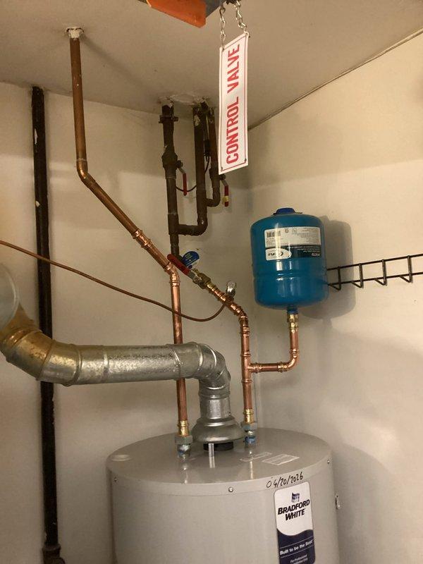 Completed installation of a 50-gallon Bradford White residential water heater in basement utility area. Connected all necessary plumbing components including galvanized and copper piping with proper fittings and elbow joints for hot and cold water supply lines. Installed blue expansion tank with brass fittings to maintain proper system pressure and protect against thermal expansion.