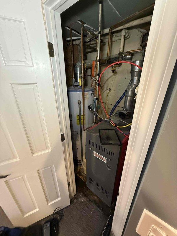 Responded to no hot water complaint and performed system inspection. Upon arrival, found boiler system with significant rust staining on drip pan and visible moisture accumulation, indicating potential leak or condensation issue. Inspected water heater, furnace connections, and associated copper piping throughout utility closet. Identified aging copper pipes with oxidation and discoloration. Checked all valves, fittings, and colored hose connections between components. Addressed immediate issue to restore hot water service and documented equipment condition for customer awareness of system age and wear patterns.