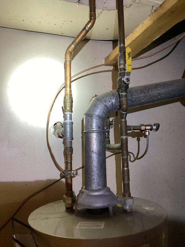Responded to service call for non-functional tanked water heater over 10 years old in residential basement utility room. Upon inspection, assessed existing unit condition and plumbing configuration including copper supply lines, pressure relief valve piping, and associated connections. Determined water heater had reached end of serviceable life and required replacement. Completed full water heater replacement including proper disconnection of existing unit, installation of new tanked water heater with code-compliant connections, pressure relief valve installation with proper discharge piping, and restoration of hot and cold water supply lines using copper piping with appropriate fittings and shut-off valves. Verified all connections for leaks, tested unit operation, and confirmed proper heating function before completing service.
