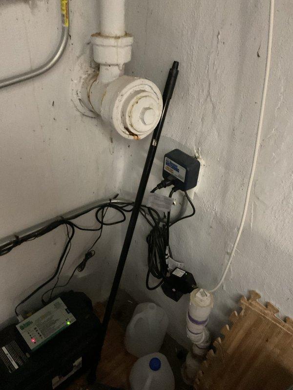 Responded to service call for battery backup sump pump system displaying error code and audible alarm despite recent battery replacement. Upon arrival, performed comprehensive inspection of 6-year-old sump pump installation including primary pump unit, backup battery system, control panel, discharge piping, and sump pit assembly. Examined electrical connections, tested float switch operation, and evaluated PVC discharge line routing and check valve functionality. Inspected battery backup control module mounted on wall, verified cable connections, and assessed monitoring display readings. Documented existing installation configuration including pit location, pump mounting, and associated plumbing components to determine root cause of system malfunction and provide recommendations for repair or replacement.