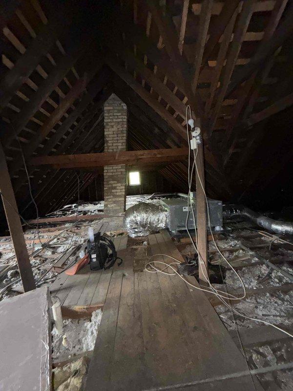 Completed routine HVAC maintenance agreement service including comprehensive air conditioning system inspection in attic space. Performed temperature diagnostics using calibrated digital thermometer, recording ambient readings at insulation surfaces to verify proper thermal performance and identify potential efficiency concerns. Inspected attic-mounted HVAC components, ductwork, and insulation integrity around chimney penetration and throughout accessible areas. Documented system conditions with photographic evidence showing work area setup, insulation configuration, and temperature measurement procedures for quality assurance records.