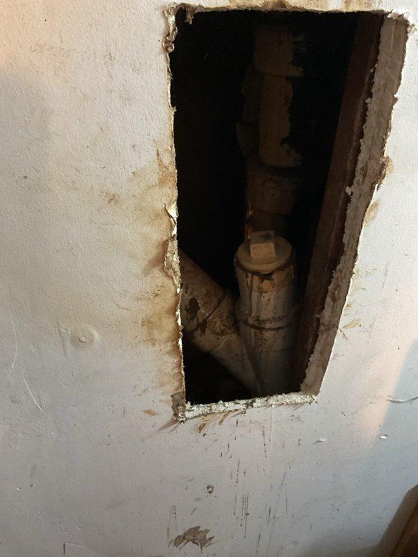 Responded to plugged sewer drain complaint at residential property. Upon arrival, accessed plumbing system through existing wall opening to inspect vertical drain stack. Wall cavity showed evidence of previous water intrusion with visible staining around access point. Vertical cast iron or galvanized steel drain pipe exhibited corrosion and aging consistent with older plumbing infrastructure. Inspected pipe coupling/joint connection within wall cavity for potential blockage points or structural compromise. Documented conditions via photography showing pipe condition, water damage patterns, and access area. Provided homeowner with diagnostic findings and discussed camera inspection options to further evaluate sewer line condition and locate blockage source. Advised on additional plumbing concerns as requested by homeowner during visit.