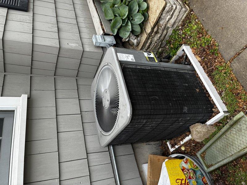 Completed emergency residential AC replacement for 15-year-old failed system. Removed existing outdoor condensing unit and installed new air conditioning system on concrete pad adjacent to building with gray siding. Unit positioned in side yard area with proper clearances maintained from structure and landscaping. Connected electrical conduit to exterior wall and verified all refrigerant lines, electrical connections, and drainage systems functioning properly. System tested and operational upon completion.