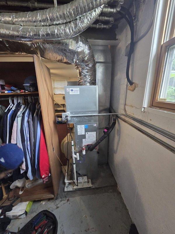 # HVAC System Installation

Completed full air conditioning system installation in basement utility area. Removed existing equipment and installed new Unico/Bosch system including outdoor condensing unit, indoor air handler, evaporator coil, and programmable thermostat. 

Mounted air handler vertically against cinder block wall with proper clearances for service access. Connected insulated flexible ductwork to unit and routed horizontally across ceiling joists to existing distribution system. Installed copper refrigerant line set between outdoor condenser and indoor coil, properly insulated and secured along wall. Ran electrical conduit from main panel to equipment locations and wired units per manufacturer specifications. Installed condensate drain line with proper pitch and trap configuration.

Pressure tested refrigerant lines for leaks, evacuated system to manufacturer specifications, and charged with appropriate refrigerant type and quantity per unit nameplate. Verified all electr