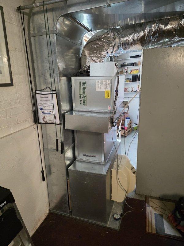 # HVAC System Installation

Completed full air conditioning system installation in basement utility area. Removed existing equipment and installed new Unico/Bosch system including outdoor condensing unit, indoor air handler, evaporator coil, and programmable thermostat. 

Mounted air handler vertically against cinder block wall with proper clearances for service access. Connected insulated flexible ductwork to unit and routed horizontally across ceiling joists to existing distribution system. Installed copper refrigerant line set between outdoor condenser and indoor coil, properly insulated and secured along wall. Ran electrical conduit from main panel to equipment locations and wired units per manufacturer specifications. Installed condensate drain line with proper pitch and trap configuration.

Pressure tested refrigerant lines for leaks, evacuated system to manufacturer specifications, and charged with appropriate refrigerant type and quantity per unit nameplate. Verified all electr