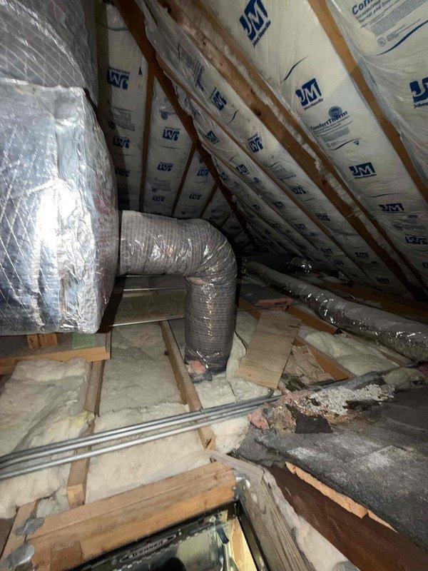 Performed comprehensive estimate for full-system HVAC replacement on second-floor zone serving top level of residence. Existing 22-year-old system located in attic space accessed via pull-down ladder. Documented current equipment dimensions and existing ductwork configuration, including silver flex duct and metallic-wrapped supply runs. Assessed attic conditions, noting Johns Manville insulation installation between rafters and available clearances for new equipment placement. Measured air handler footprint to determine proper sizing and compatibility for replacement unit installation.