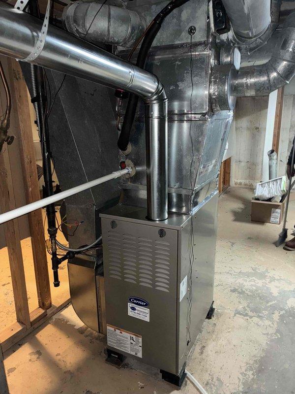 Completed full replacement of two Carrier brand furnaces and one humidifier system in residential basement mechanical room. Removed existing equipment and installed new furnace units with proper venting and ductwork connections. Connected metallic supply ductwork including rigid galvanized sections and flexible insulated ducts to distribution system. Installed PVC condensate drainage piping and verified proper routing. Secured all electrical connections and control wiring to furnace units. Tested system operation and airflow distribution throughout ductwork network to ensure proper heating functionality.