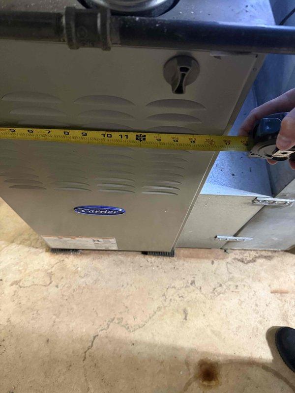 Provided estimate for replacement of two existing Carrier outdoor condensing units serving residential property. One unit approximately 12 years old and second unit 25-30 years old both requiring replacement. Existing 9-year-old Carrier furnace with connected evaporator coil to remain in service. Both outdoor units have standard accessibility for replacement. Measured existing equipment dimensions and documented current system configuration in basement mechanical room including furnace, ductwork, and connected components.