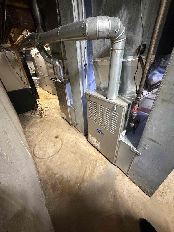 Provided estimate for replacement of two existing Carrier outdoor condensing units serving residential property. One unit approximately 12 years old and second unit 25-30 years old both requiring replacement. Existing 9-year-old Carrier furnace with connected evaporator coil to remain in service. Both outdoor units have standard accessibility for replacement. Measured existing equipment dimensions and documented current system configuration in basement mechanical room including furnace, ductwork, and connected components.