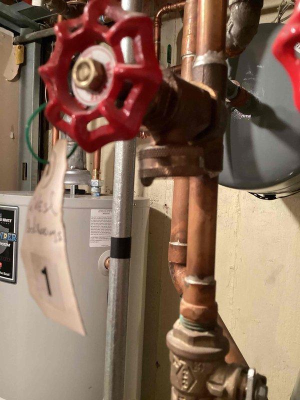 Responded to service call for leaking valves on hydronic heating system. Upon arrival, inspected boiler manifold assembly and associated zone valves in basement mechanical room. Identified multiple leaking spigots on the copper piping manifold with red-handled isolation valves. Tightened packing nuts on affected valve stems and replaced deteriorated valve packing where necessary. Tested all zone valves for proper operation and verified no additional leaks present throughout the system. Placed collection buckets as temporary measure during initial assessment. System restored to normal operation with all leaks eliminated prior to homeowner's scheduled travel.