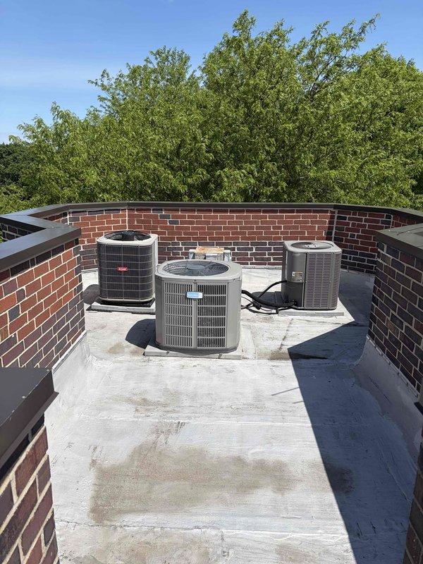 Conducted HVAC estimate for air conditioning system replacement at residential condominium unit. Evaluated existing 11-year-old rooftop AC condenser unit showing signs of age and wear, with visible dust accumulation on internal components. Assessed rooftop installation configuration with multiple HVAC units positioned on flat concrete surface within brick parapet enclosure, documented equipment specifications and existing installation conditions to provide replacement system recommendations.