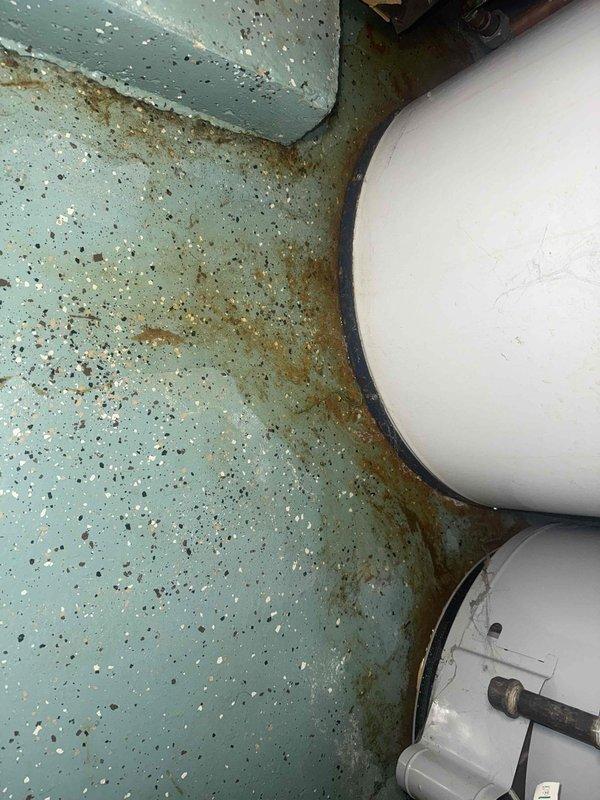 Responded to emergency call for tanked water heater failure resulting in complete loss of hot water. Upon arrival, found water heater in severely deteriorated condition with extensive water damage to surrounding floor area and visible corrosion staining throughout the installation space. Unit exhibited signs of catastrophic failure with significant moisture intrusion and long-term neglect. Documented existing conditions through photographic evidence showing rust-colored staining patterns on floor surface, damaged equipment housing, and compromised internal components. Assessed water heater system and confirmed unit was beyond repair, requiring full replacement. Provided customer with emergency service during evening hours to address immediate hot water restoration needs.