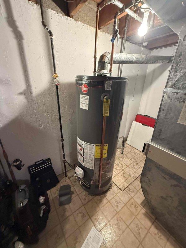 Responded to emergency service call for a one-year-old gas water heater experiencing improper venting issues. Upon arrival, inspected the Rheem brand water heater installation in the basement utility room and assessed the complete venting system running through the ceiling joists and attic space. Examined the existing vent pipe configuration, including the flexible ductwork, rigid metal ductwork components, and all connection points from the appliance draft hood through the termination point. Identified venting deficiencies preventing proper exhaust of combustion gases. Corrected the venting system to ensure proper draft and compliance with manufacturer specifications and local code requirements. Verified all duct connections were properly sealed and secured. Tested the water heater operation, confirmed proper venting function, and verified adequate combustion air supply. System restored to safe operating condition with proper exhaust ventilation established.