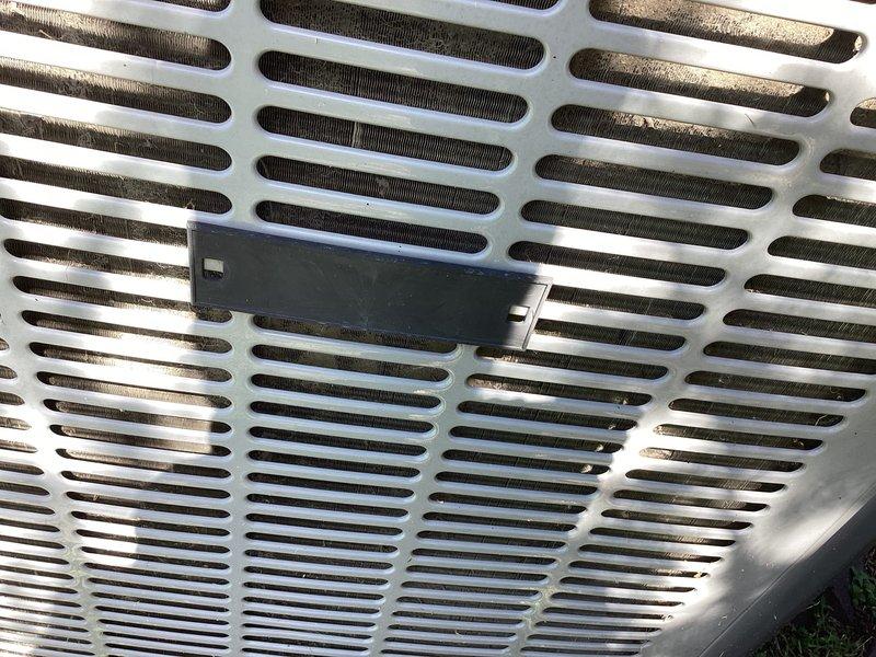Responded to no cooling complaint on residential air conditioning system. Upon arrival, performed visual inspection of outdoor condensing unit located on ground-level pad adjacent to brick exterior. Unit appeared to be in serviceable condition with normal weathering. Examined condenser cabinet, coil access panels, and ventilation grilles for any obvious signs of mechanical failure or damage. Verified unit identification and specifications from manufacturer nameplate. Documented equipment condition through photographs showing exterior cabinet, top grille assembly, and mounting hardware. Cleared vegetation growth from around unit base to ensure proper airflow and drainage. Assessed condenser fan grille for debris accumulation and verified structural integrity of cabinet panels and fasteners.