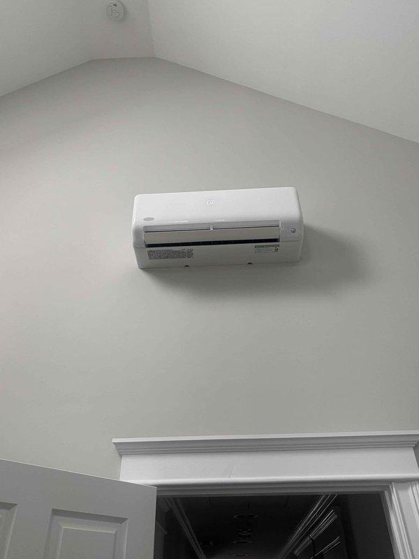 Completed installation of single-zone ductless mini-split air conditioning system at residential property. Mounted outdoor condensing unit on concrete pad at exterior foundation with proper clearances, ran insulated refrigerant line sets along base of structure, and installed indoor wall-mounted air handler unit in upper room with vaulted ceiling. System was properly commissioned, tested for proper operation, and left in full working condition.
