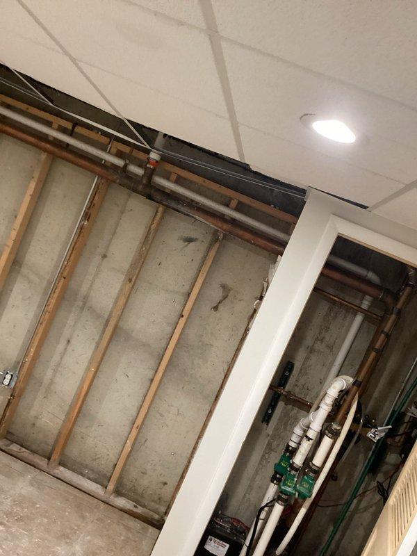 Completed inspection of waste copper piping in basement utility area. Identified active leak in horizontal copper waste line requiring replacement. Documented existing plumbing infrastructure including exposed copper piping, PVC drainage system, and water heater installation for service records.