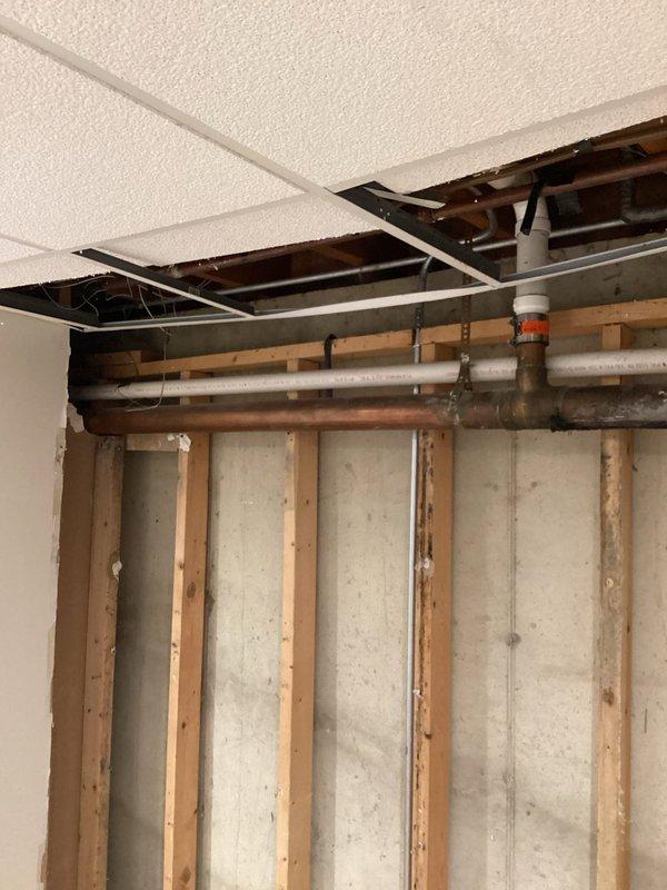 Completed inspection of waste copper piping in basement utility area. Identified active leak in horizontal copper waste line requiring replacement. Documented existing plumbing infrastructure including exposed copper piping, PVC drainage system, and water heater installation for service records.