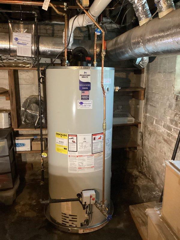 Installed a new 75-gallon Bradford White residential water heater in basement utility area. Performed complete water heater replacement including all necessary copper supply line connections with brass fittings and valves, installed recirculation pump with electrical connections, and connected required PVC venting. Unit was properly positioned on concrete floor, all plumbing connections were secured and tested for leaks, and system was commissioned and verified operational.