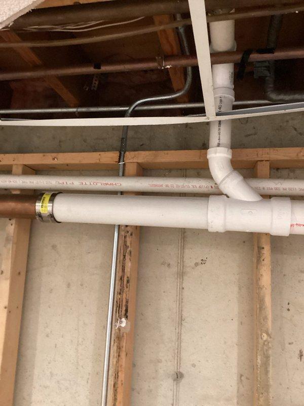 Replaced failed copper drain piping with PVC drainage system in basement utility area. Installation included proper fitting connections, secure mounting to concrete block wall, and integration with existing plumbing infrastructure. Work completed in compliance with applicable plumbing codes.