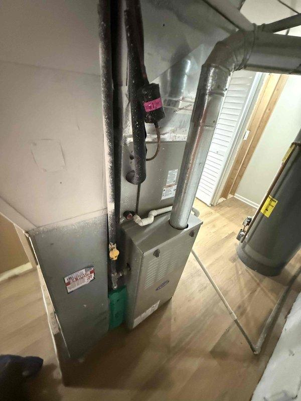 Completed routine HVAC maintenance agreement service on split system including outdoor condensing unit and indoor air handler/furnace. Performed comprehensive system inspection, verified proper operation of all components, and documented equipment condition with photos showing outdoor unit positioned against brick wall with moss growth on surrounding surfaces and indoor equipment installation in utility closet with connected ductwork and piping.