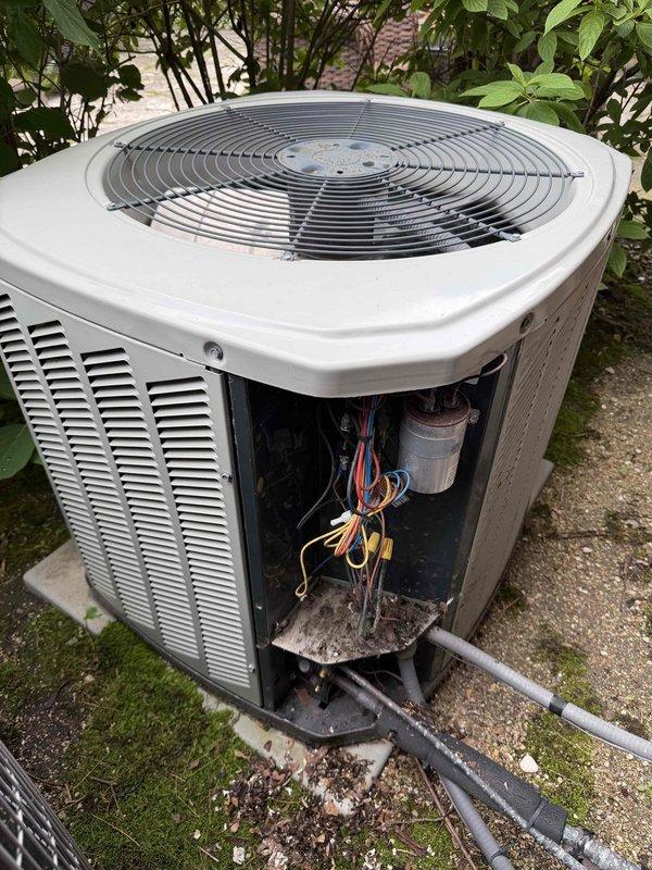 # HVAC Service Report

Responded to no cooling complaint on residential air conditioning system. Upon arrival, found outdoor condenser unit operational but system not producing adequate cooling. Removed front access panel to inspect internal electrical components and capacitor. Verified proper refrigerant line connections and electrical conduit routing. Unit showed normal outdoor weathering with minor debris accumulation in base pan. System located on concrete pad with proper clearances maintained from surrounding landscaping and building structure.