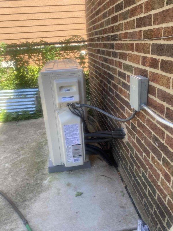 Completed final warranty installation of residential HVAC heat pump system. Verified proper placement of outdoor condensing unit on concrete pad with secure refrigerant line connections, electrical conduit routing, and disconnect box mounted to exterior wall per code requirements. Confirmed indoor basement installation components are properly positioned with all mechanical connections secured and system ready for operation.