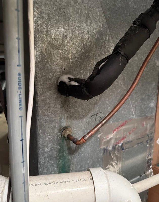 Responded to a no cooling call and diagnosed a refrigerant leak at the air handler suction line copper fitting, evidenced by green oil staining. The leak location was easily accessible in the basement utility area. Documented the refrigerant leak with photos showing the affected copper piping and brass fittings at the air handler connection point.