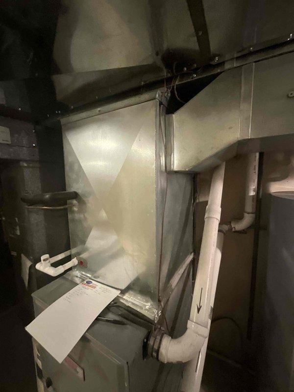 Conducted comprehensive assessment of existing residential HVAC system located in basement utility area for full system replacement quote. Evaluated current furnace unit, ductwork configuration including galvanized metal plenum and flexible ducting sections, condensate pump assembly with PVC drainage lines, and overall mechanical room layout. Documented equipment condition showing age-related wear, dust accumulation on duct components, and existing installation configuration with water heater proximity. Photographed complete system setup to provide detailed visual reference for replacement specifications and equipment sizing requirements.