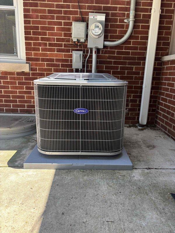 Completed full air conditioning system replacement including outdoor condensing unit and indoor evaporator coil. Removed existing equipment and installed new Carrier brand condenser unit on composite pad against exterior brick wall. Connected refrigerant lines, electrical service, and condensate drainage. Performed proper evacuation of refrigerant system, achieving vacuum level of 93 microns as verified with digital manifold gauge, ensuring system integrity and absence of moisture or contaminants. Energized system and confirmed proper operation of all components.