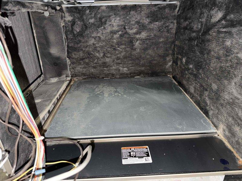Returned to property for third blower wheel cleaning as part of comprehensive system maintenance. Accessed air handler unit and documented extensive contamination including heavy dust accumulation and mold growth on interior surfaces and compartment walls. Removed blower wheel assembly from unit and performed thorough cleaning to restore proper airflow and system efficiency. Component exhibited significant debris buildup that was affecting system performance. Cleaned and reinstalled blower wheel, ensuring proper operation before closing unit.