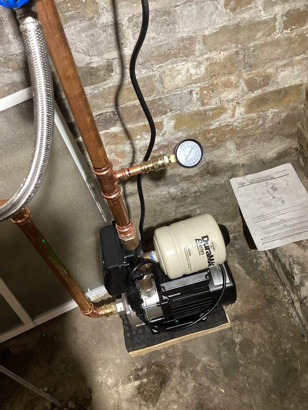 Completed installation of RPZ backflow preventer and booster pump system for residential irrigation. Mounted pump assembly on concrete pad in basement utility area with proper electrical connection and integrated pressure tank. Installed copper piping with soldered joints, pressure gauge, braided stainless steel flex connector, and shutoff valves to ensure code-compliant operation and system protection.