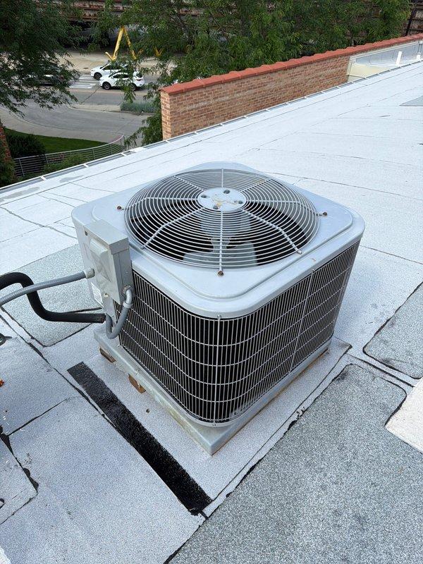 Completed comprehensive maintenance service on rooftop-mounted air conditioning system accessible via ladder from upper deck. Performed full system inspection of condenser unit including visual assessment of cabinet condition, refrigerant line connections, and rooftop installation integrity. Inspected copper refrigerant lines for proper insulation and signs of wear or damage, verified secure mounting of condensing unit on rooftop platform, and confirmed proper drainage around equipment. Checked condenser coil fins for debris accumulation, assessed fan guard and top grille condition, and documented equipment specifications from manufacturer labels. All components found in good operational condition with no immediate service needs identified. System operating within normal parameters upon completion of maintenance agreement inspection.