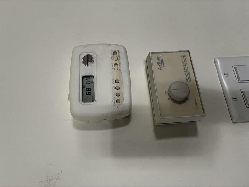 Evaluated first floor air conditioning system approximately 20 years old with reported cooling failure. Documented existing thermostat and humidity control equipment showing significant age-related deterioration and ceiling damage around mounted components. Provided estimate for complete HVAC system replacement due to unit age and lack of cooling capacity.