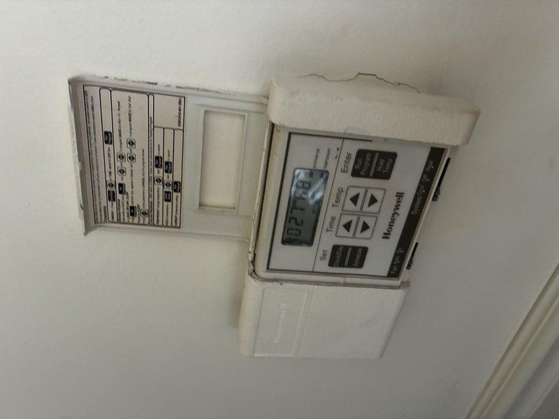 Evaluated first floor air conditioning system approximately 20 years old with reported cooling failure. Documented existing thermostat and humidity control equipment showing significant age-related deterioration and ceiling damage around mounted components. Provided estimate for complete HVAC system replacement due to unit age and lack of cooling capacity.